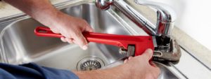 Plumber using a wrench on a kitchen faucet | Kitchen sink plumbing in Longwood, FL by Advantage Plumbing